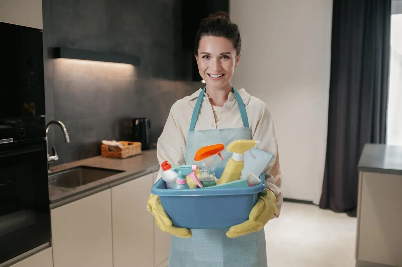 Темноволосая женщина несет таз с дезинфицирующими приборами.